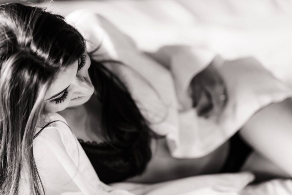 Woman in black lace bra and white shirt, standing in a softly lit room during a boudoir photography session in Phoenix.